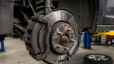 Close-up of damaged car brake rotor and worn brake caliper in repair garage